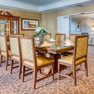 An elegant dining room featuring a wooden table set with six chairs and decorative elements such as flowers and artwork.