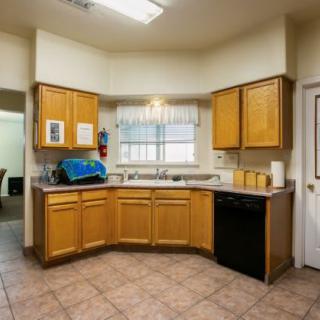 A kitchen interior featuring wooden cabinets, a sink, and tiled flooring.
