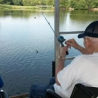 A person fishing by a lake on a sunny day.