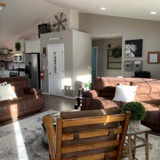 A cozy and sunlit living area with modern decor, featuring comfortable sofas and an open kitchen.