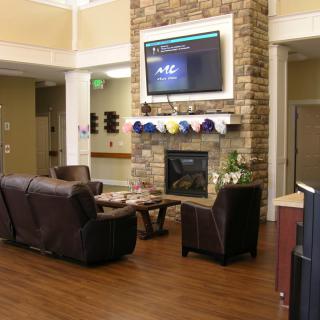 A cozy lounge area featuring comfortable seating, a fireplace, and a mounted television.