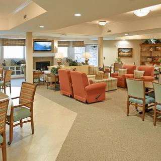 A cozy and well-furnished lounge area with chairs, tables, and warm lighting.
