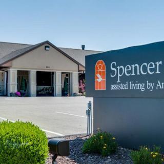 A view of an assisted living facility with a sign and parking area in front.