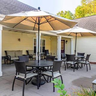 A cozy outdoor patio with tables, chairs, and large umbrellas for shade.