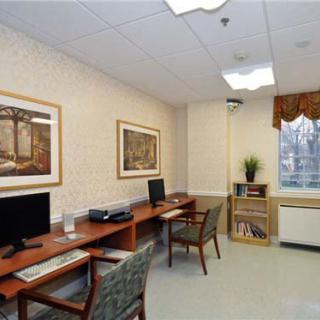 A small office space featuring two desks with computers, chairs, and framed artwork on the walls.