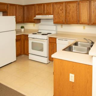 A cozy kitchen with wooden cabinets and standard appliances.