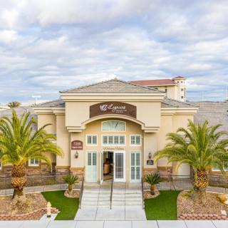 A well-maintained building entrance with palm trees and a cloudy sky backdrop.