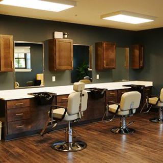 An empty barbershop with rows of chairs and mirrors.