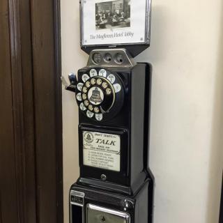 A vintage rotary payphone mounted on a wall.