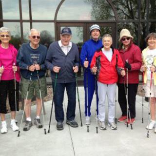 A group of seniors enjoying a walk with poles outdoors.