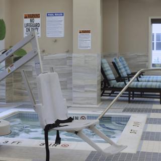 An indoor pool area with a handicap lift and seating.