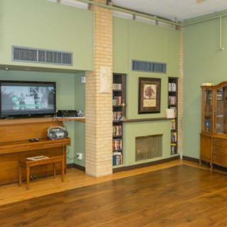 A cozy living room with a TV, bookshelf, and wooden cabinet on hardwood flooring.