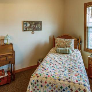A cozy bedroom with a single bed, small desk, and a window providing natural light.