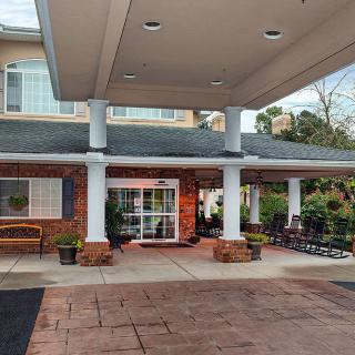 The entrance of a building with a covered canopy and potted plants lining the walkway.