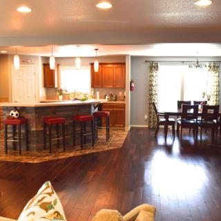 A modern open floor plan featuring a kitchen with bar stools and a connected dining area.