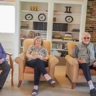 A serene gathering of three seniors enjoying each other's company in a cozy living room.