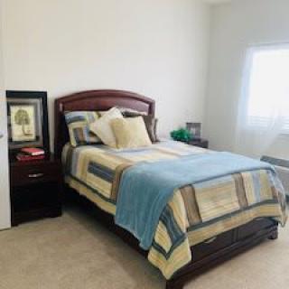 A neatly arranged bedroom with a bed, nightstand, and decor.