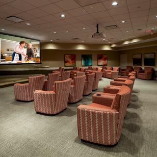 A cozy indoor movie theater with comfortable seating arranged in front of a large projector screen.