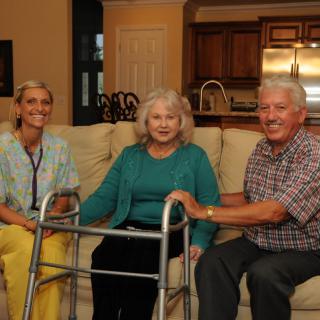 Elderly woman seated with a walker, accompanied by family members in the living room.