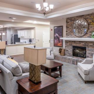 A modern and cozy living room with an open layout, featuring a stone fireplace and elegant furniture.
