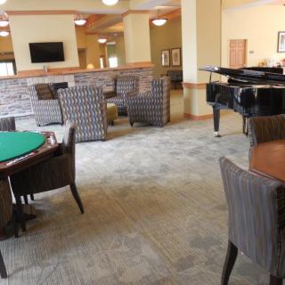 A comfortable lounge area featuring a piano, tables, and chairs.