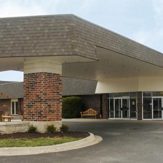 A modern building entrance featuring a large canopy supported by brick columns.