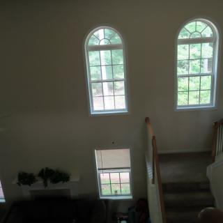 A view of a living room with large arched windows and a staircase.