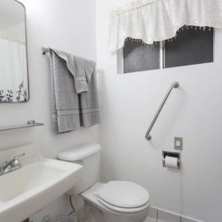 A clean and simple bathroom with a toilet, sink, and a grab bar for accessibility.