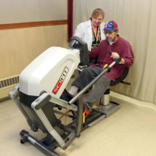 A therapist assists a patient using an exercise machine for rehabilitation.