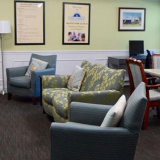 A cozy living area featuring comfortable armchairs, a patterned sofa, and framed artworks on the wall.