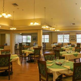A spacious dining room with neatly arranged tables and chairs, softly lit with hanging lights.