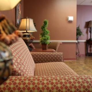 A cozy waiting room with patterned sofas, warm lighting, and decorative plants.