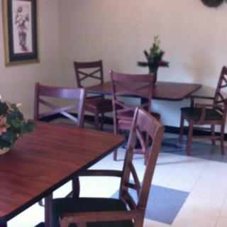 A cozy dining area with wooden tables and chairs, decorated with plants.