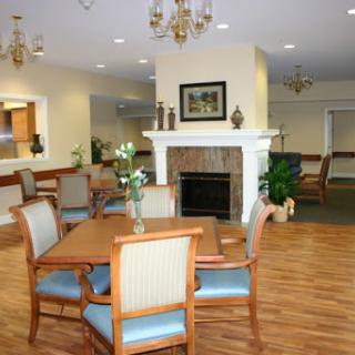 A cozy lounge area featuring comfortable seating around a dining table, complemented by a fireplace and elegant chandeliers.