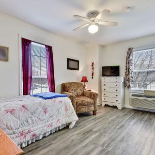 A cozy bedroom with a single bed, armchair, and dresser under a ceiling fan.