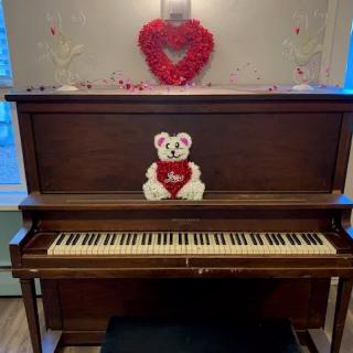 A decorated piano featuring a teddy bear and heart for Valentine's Day ambiance.