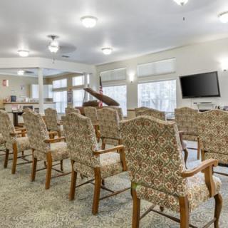 A well-lit conference room with rows of patterned chairs and a wall-mounted television.