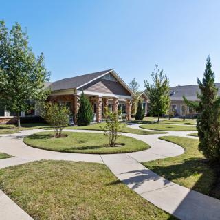 A suburban house with a landscaped yard and winding pathways on a sunny day.