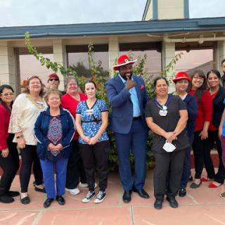 A cheerful gathering of community members dressed in red and blue, celebrating together outdoors.