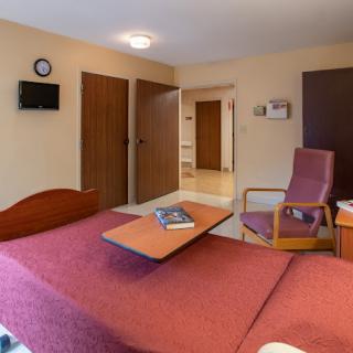 A cozy hotel room featuring a bed, chair, and wall-mounted television.