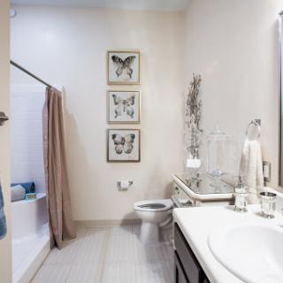 A modern bathroom featuring butterfly artwork, a clean vanity area, and a cozy shower space.