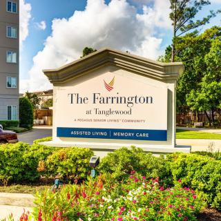 A sign for The Farrington at Tanglewood with a landscaped area and building in the background.