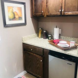 A small kitchen corner featuring a countertop with cups on a tray, paper towels, and decorative items.