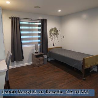 A minimalist bedroom with a single bed, modern curtains, and wood flooring.