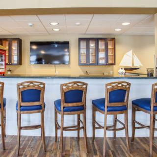 A stylish bar setting with wooden chairs and a large television.