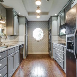A modern kitchen with sleek cabinetry and wood flooring, featuring a circular window for natural light.