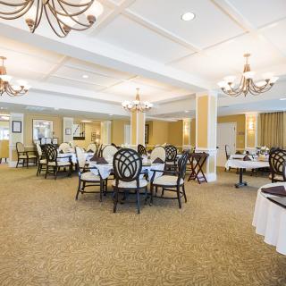 An elegant dining area with neatly arranged tables and chairs, adorned with chandeliers.