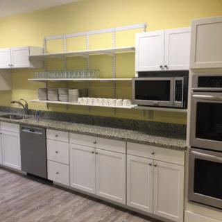 A modern kitchen with white cabinets, stainless steel appliances, and open shelves.