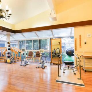 A spacious rehabilitation center equipped with various exercise machines and therapy tools.