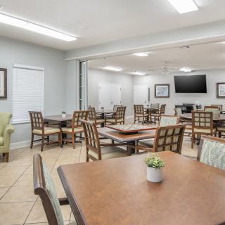 A modern dining room with multiple tables, chairs, and a wall-mounted television.